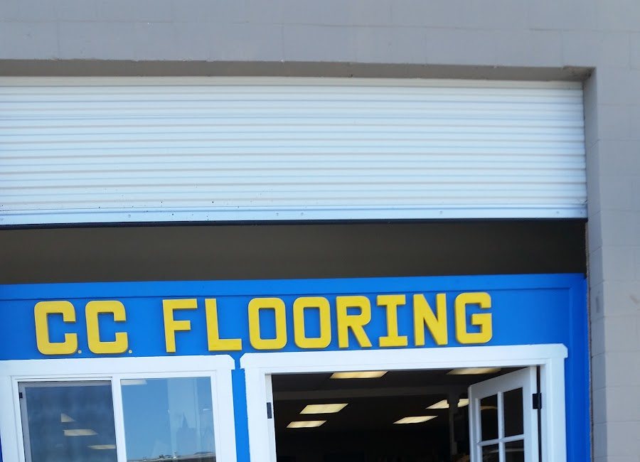 The shop front on Tank Farm Road: C.C. Flooring lettered in yellow on a bright blue fascia.