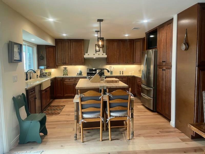 A kitchen with dark stained wood cabinets, a lighter island and a pale hardwood floor.